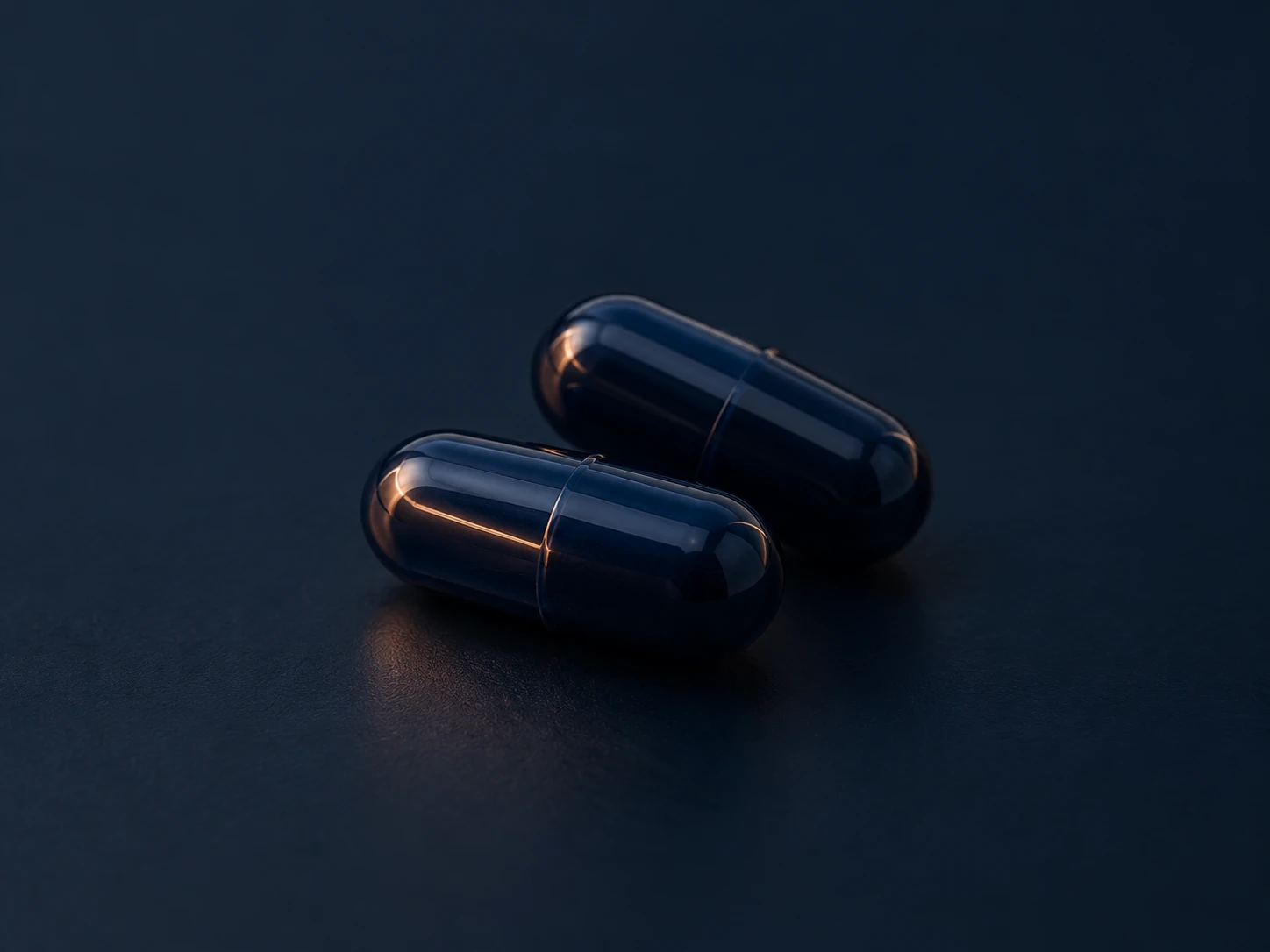 Two dark navy capsules on a dark table